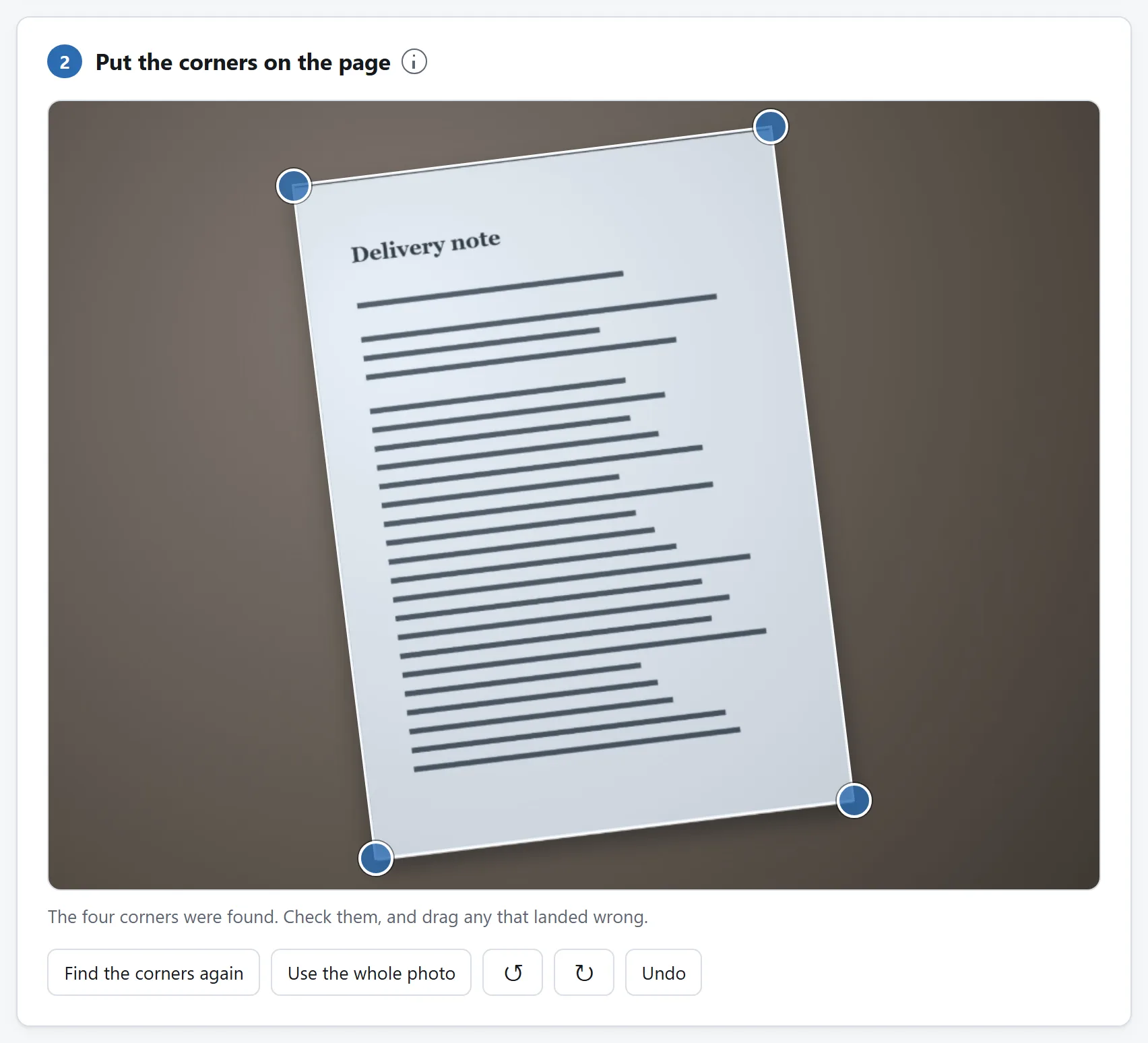 A photograph of a page on a desk, taken at an angle, with a detected quadrilateral drawn over its corners and handles for adjusting them.